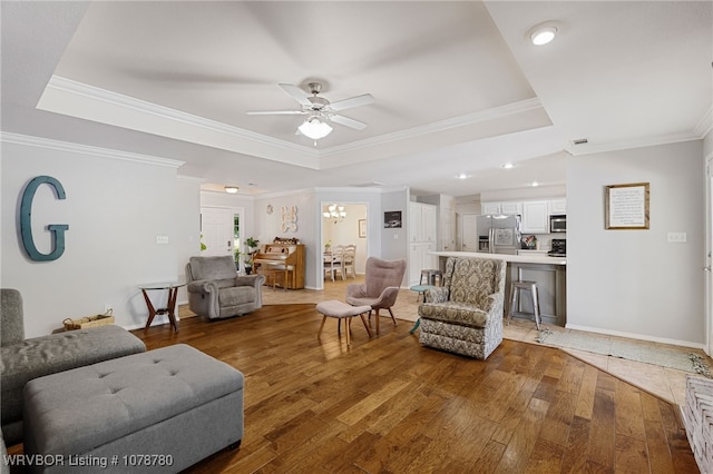 living room with hardwood / wood-style flooring, a tray ceiling, and crown molding