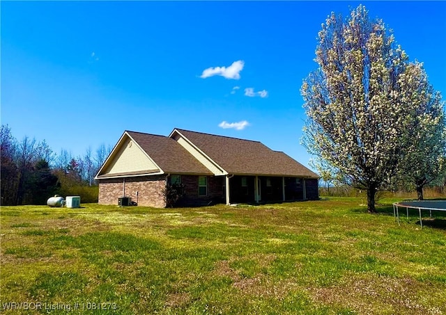 195 Polk 492, Cove, AR 71937 - rear view of property with a trampoline, a yard, central AC unit, and brick siding
