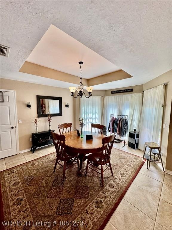 195 Polk 492, Cove, AR 71937 - dining room featuring a tray ceiling, a textured ceiling, light tile patterned flooring, a chandelier, and baseboards