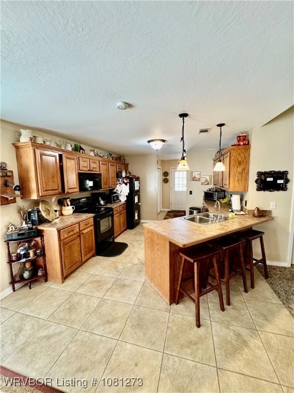 195 Polk 492, Cove, AR 71937 - kitchen with black appliances, a peninsula, a kitchen breakfast bar, a sink, and brown cabinets