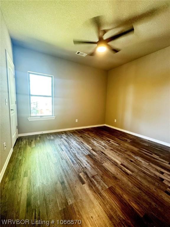 unfurnished room featuring ceiling fan, dark hardwood / wood-style flooring, and a textured ceiling