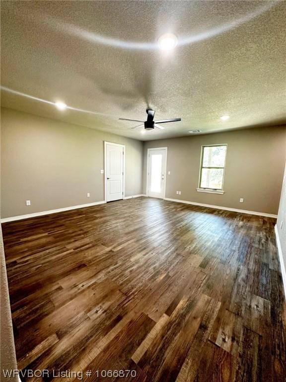 empty room featuring dark hardwood / wood-style floors, ceiling fan, and a textured ceiling