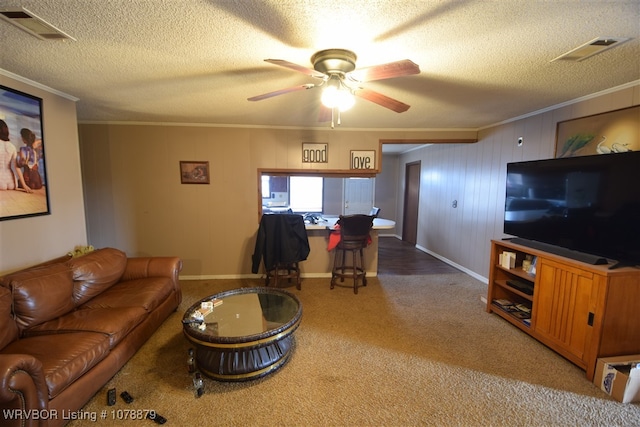 living room featuring ornamental molding, carpet floors, ceiling fan, and a textured ceiling