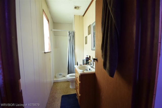 bathroom featuring vanity, toilet, wood walls, and walk in shower