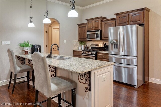 5707 Callaway Ln, Fort Smith, AR 72916 - kitchen with appliances with stainless steel finishes, arched walkways, dark wood finished floors, light stone counters, and a kitchen bar