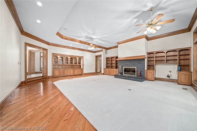 unfurnished living room featuring ceiling fan, a fireplace, ornamental molding, and light hardwood / wood-style flooring