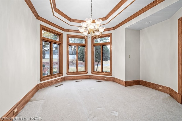 empty room with a notable chandelier, ornamental molding, carpet floors, and a tray ceiling