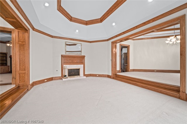 unfurnished living room with a raised ceiling, carpet floors, a notable chandelier, and ornamental molding