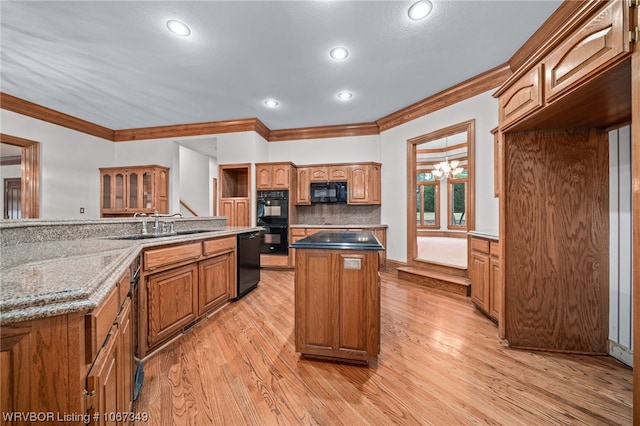 kitchen with backsplash, light hardwood / wood-style flooring, a kitchen island, and black appliances