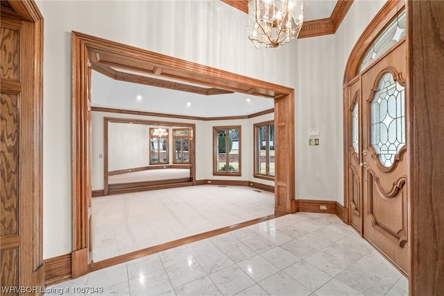 entryway with a notable chandelier and crown molding