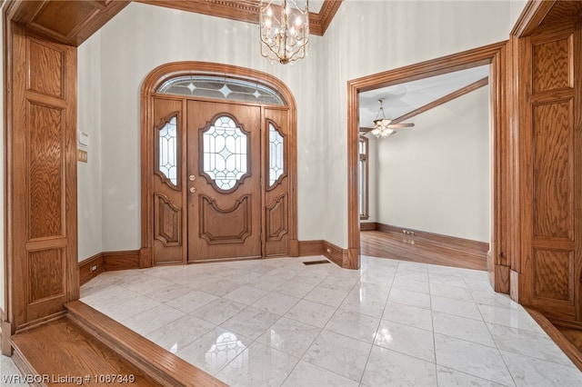 foyer entrance with crown molding and ceiling fan with notable chandelier