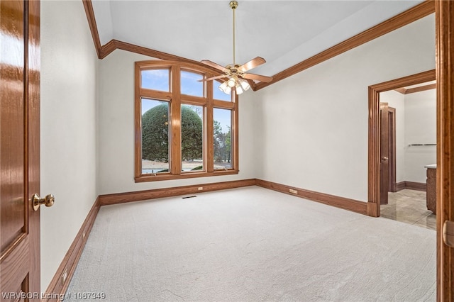 empty room with light colored carpet, vaulted ceiling, ceiling fan, and ornamental molding