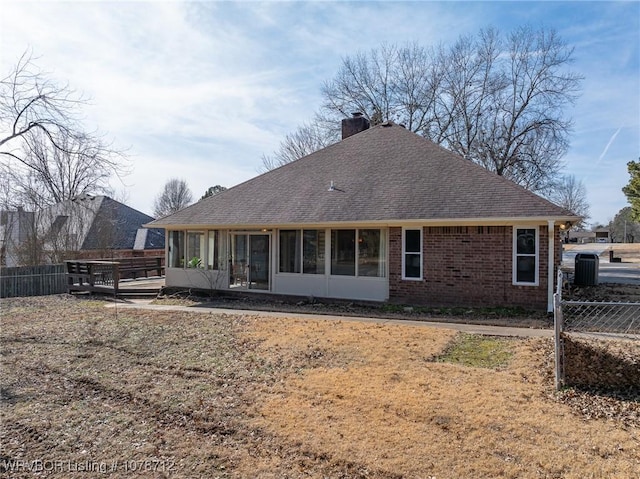 rear view of property featuring a sunroom and central AC