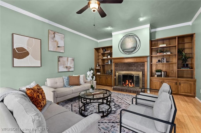 living room with a fireplace, crown molding, light hardwood / wood-style flooring, and ceiling fan