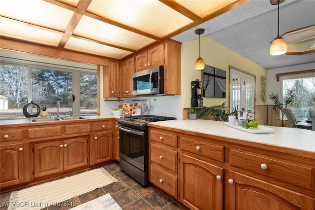 kitchen with appliances with stainless steel finishes, sink, a textured ceiling, and decorative light fixtures