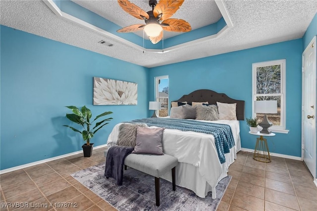 tiled bedroom featuring ceiling fan, a raised ceiling, and a textured ceiling