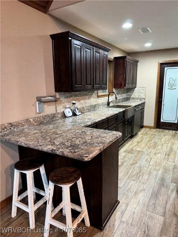 185 Susie Ln, Mena, AR 71953 - kitchen with dishwasher, backsplash, sink, light hardwood / wood-style flooring, and a kitchen bar