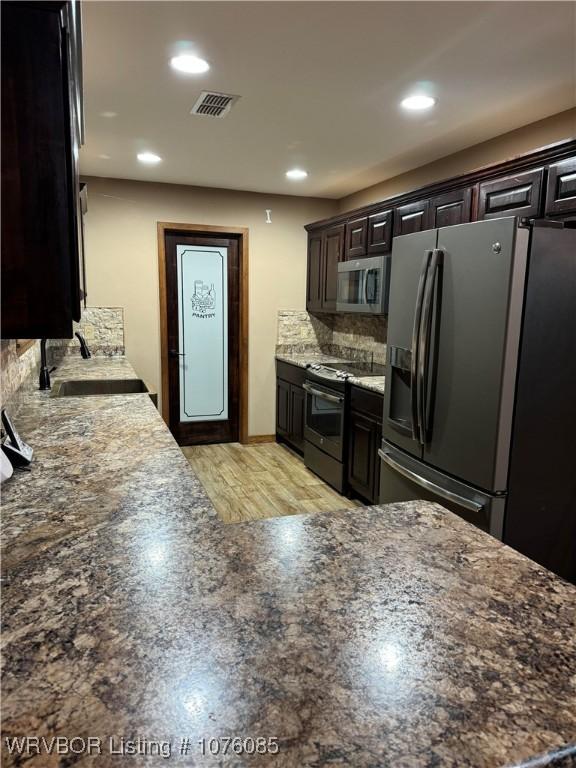 185 Susie Ln, Mena, AR 71953 - kitchen featuring sink, tasteful backsplash, dark stone counters, dark brown cabinets, and appliances with stainless steel finishes