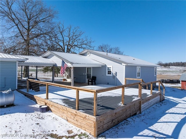 snow covered property featuring metal roof and a deck