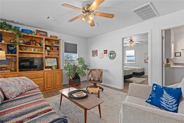 living area with light wood-style floors, a healthy amount of sunlight, and visible vents