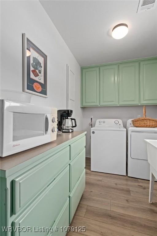 clothes washing area featuring laundry area, light wood-type flooring, washing machine and clothes dryer, and visible vents