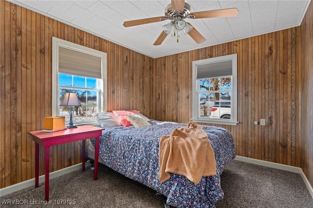 carpeted bedroom with baseboards, ceiling fan, and wooden walls