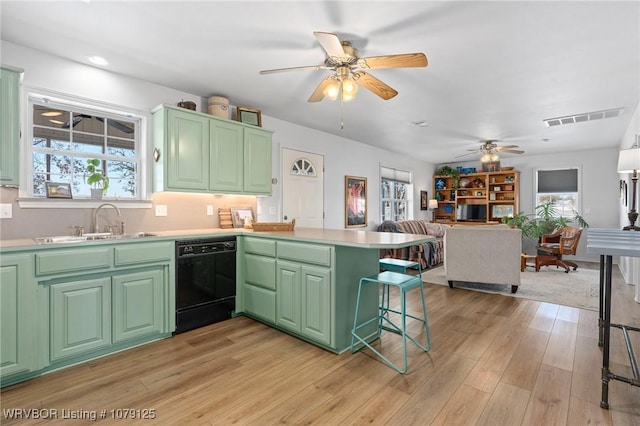 kitchen featuring light countertops, green cabinetry, dishwasher, and a peninsula