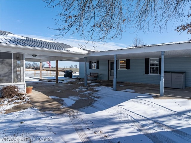 view of front of home featuring metal roof, an attached carport, and concrete driveway