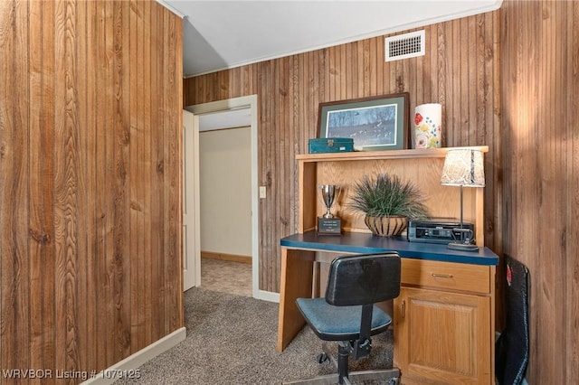 carpeted office space with wood walls, baseboards, and visible vents