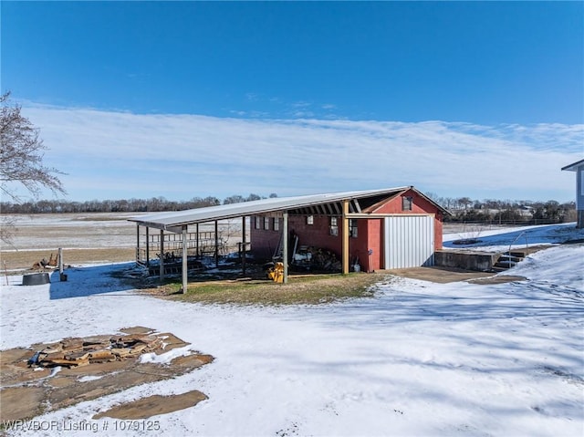 snow covered structure with an outbuilding and a pole building