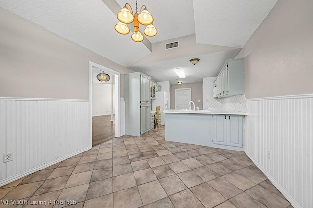 1129 Arapahoe Dr, Van Buren, AR 72956 - kitchen with a peninsula, a chandelier, a wainscoted wall, light countertops, and light tile patterned floors