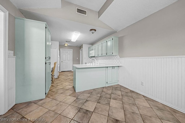 1129 Arapahoe Dr, Van Buren, AR 72956 - kitchen with a peninsula, white appliances, wainscoting, light countertops, and light tile patterned floors