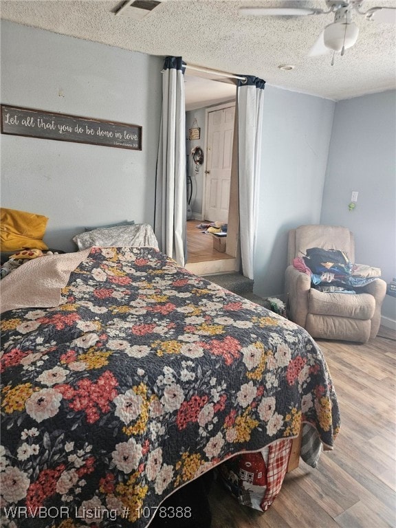 bedroom featuring a textured ceiling, ceiling fan, and wood-type flooring