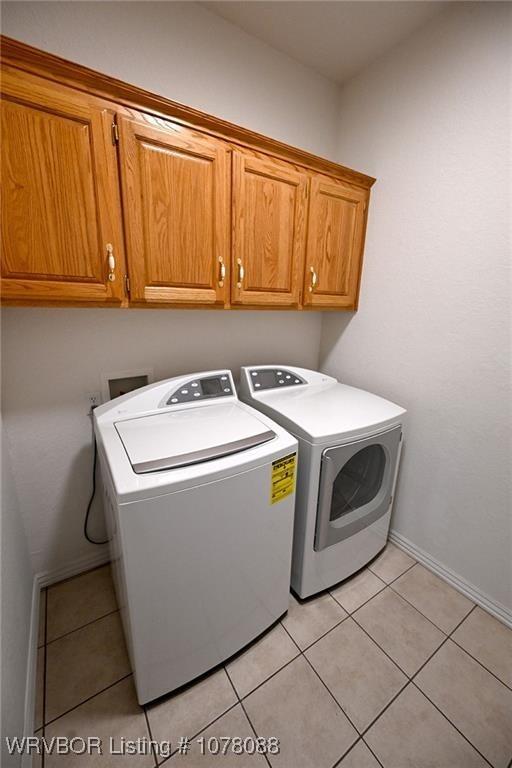 laundry area with washer and clothes dryer, light tile patterned floors, and cabinets