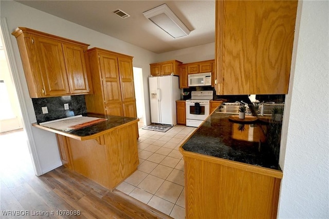 kitchen featuring white appliances, a kitchen breakfast bar, sink, tasteful backsplash, and kitchen peninsula