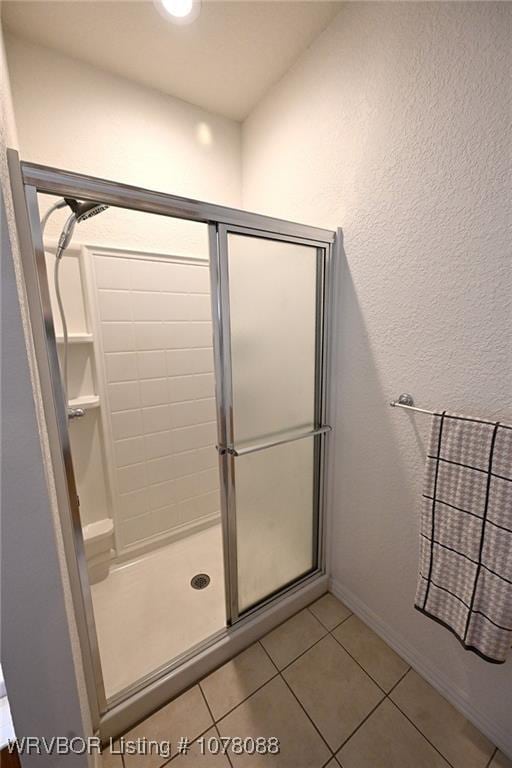 bathroom with tile patterned flooring and a shower with shower door