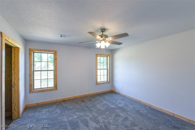 empty room featuring dark colored carpet, a textured ceiling, and ceiling fan