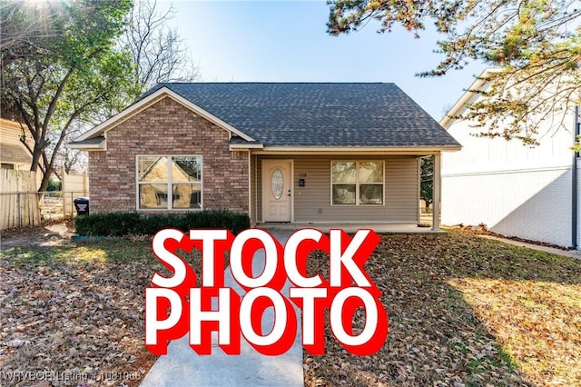 view of front of property with roof with shingles, fence, brick siding, and a porch