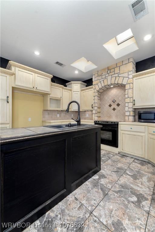 kitchen featuring backsplash, a skylight, sink, and black electric range oven