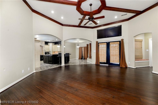 unfurnished living room featuring beam ceiling, ceiling fan, a towering ceiling, and dark hardwood / wood-style floors