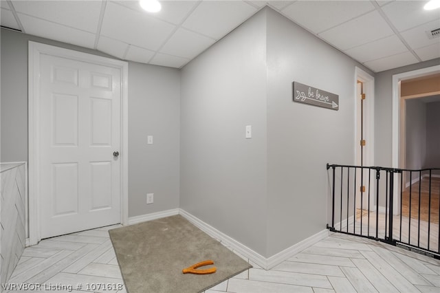 hall featuring a drop ceiling and light parquet flooring