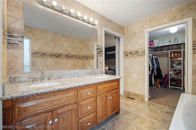 bathroom with a bathing tub, vanity, and tile walls