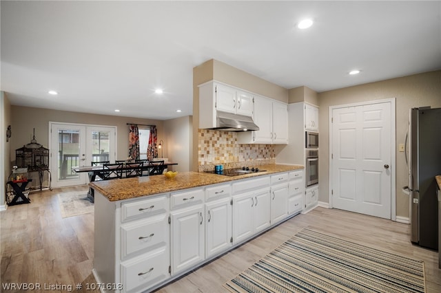 kitchen with light stone countertops, french doors, kitchen peninsula, white cabinets, and appliances with stainless steel finishes