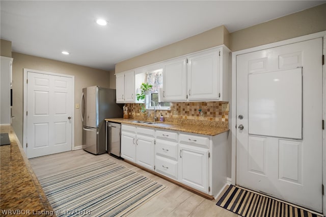 kitchen featuring backsplash, white cabinetry, sink, and appliances with stainless steel finishes