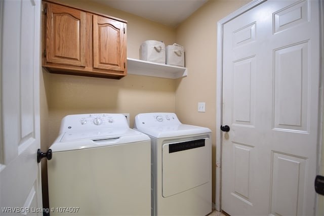 laundry area featuring washing machine and clothes dryer and cabinets