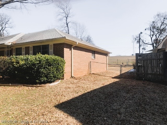 view of side of home featuring brick siding and fence