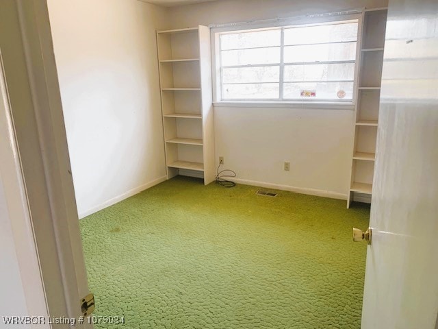 carpeted spare room with visible vents and baseboards