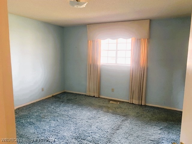 carpeted empty room with baseboards and a textured ceiling