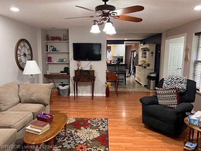 living room featuring ceiling fan, light hardwood / wood-style floors, and built in features