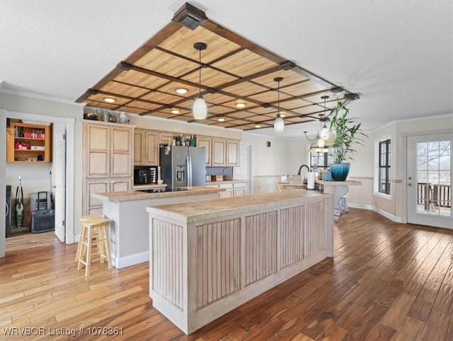 kitchen featuring light hardwood / wood-style flooring, hanging light fixtures, a center island with sink, stainless steel fridge with ice dispenser, and light brown cabinets